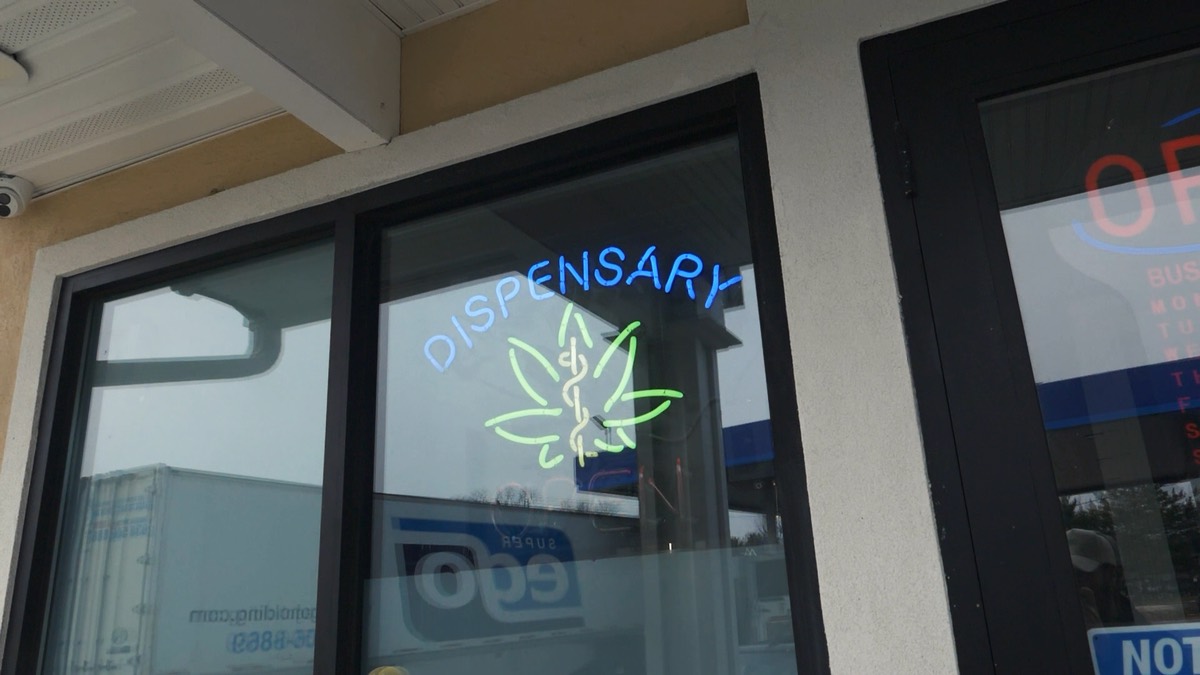 A neon sign reading Dispensary Open with a cannabis leaf, glowing in the window of the Middletown Indoor entrance.
