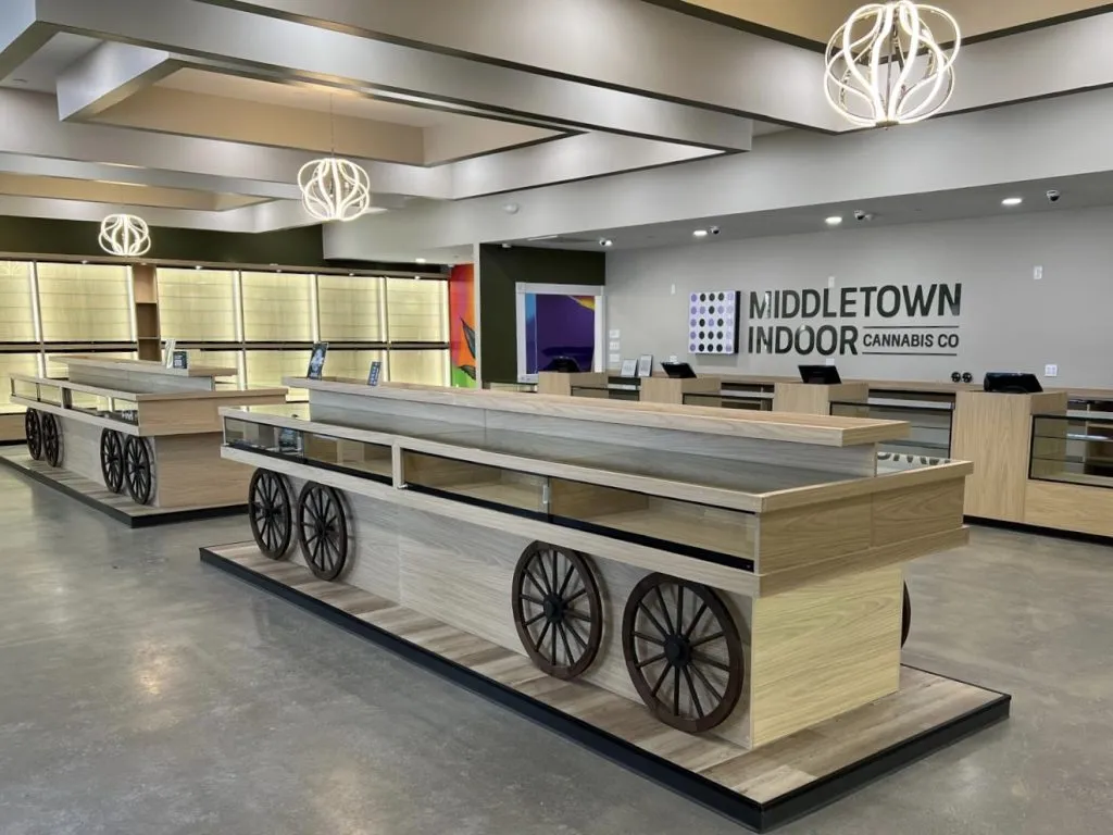 Light wood display cases on wagon wheels and the dot logo on the back wall.