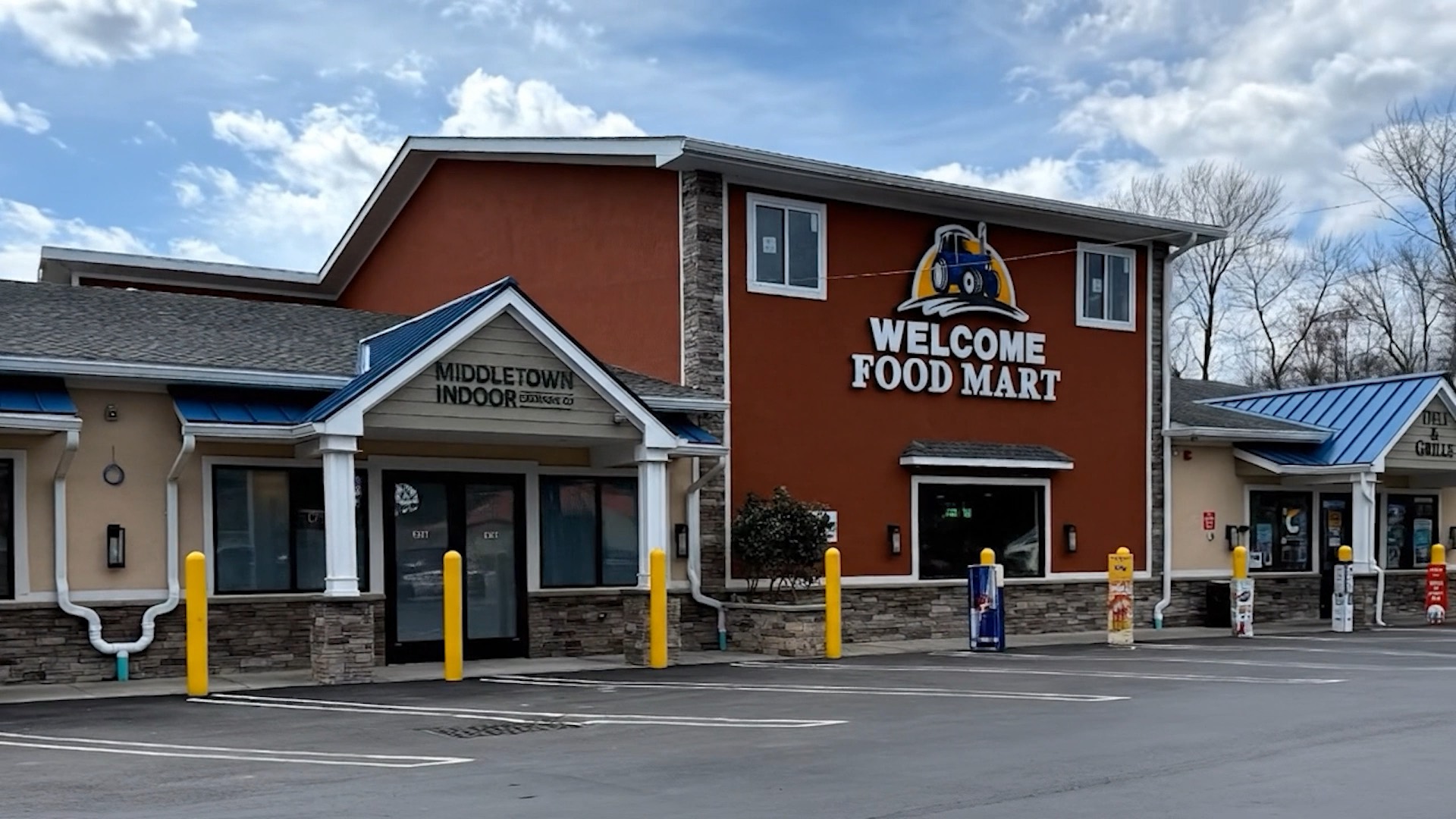 The shared building: the Middletown Indoor entrance under a gable on the left, Welcome Food Mart with its tractor logo in the center, and parking out front.